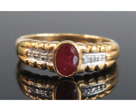 A modern 9ct gold, ruby and diamond dress ring, the oval cut ruby in a rubover setting, the shoulders each set with three dia