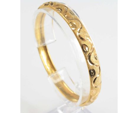 A Middle-Eastern yellow metal frosted and engraved 'slave' bangle, indistinctly marked but tests as approx 22ct, 13.2g, dia.6