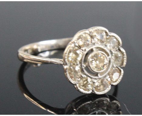 An 18ct white gold diamond circular cluster ring, featuring ten old European cut diamonds in millegrain settings, with tapere