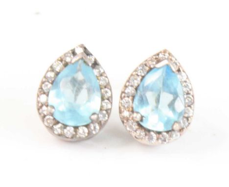 A pair of white metal pear shaped cluster earrings, each with a pear shaped blue topaz within a border of eighteen round colo