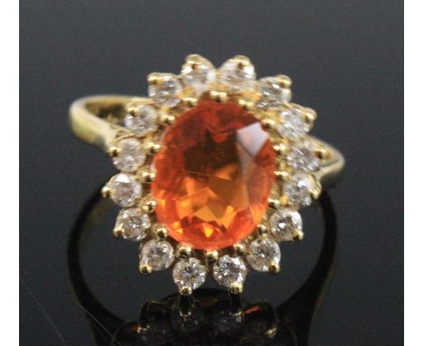 An 18ct yellow gold, opal and diamond oval cluster ring, featuring a centre oval fire opal within a border of 16 round brilli