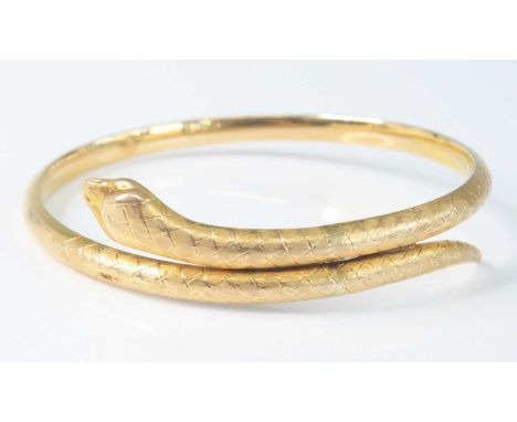 A yellow metal snake bangle, having finely engraved decoration, indistinctly marked but tests as approx 9ct, 12.3g, dia.8cm