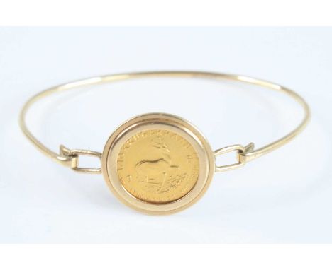 A 9ct gold bangle set with a 1/10th gold krugerrand dated 1981, gross weight 7.7g