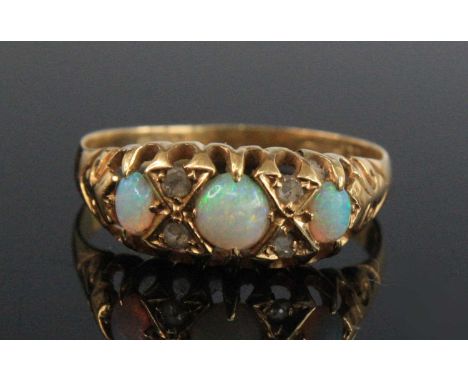 A George V 18ct gold, opal and diamond dress ring, arranged as three opal cabochons each dispersed by two small rose cut diam