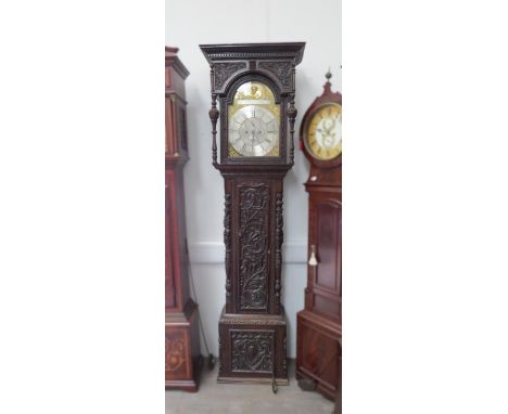 An 18th Century heavily carved oak longcase clock with silvered Roman chapter ring, date and seconds dials, sign Henry Hardin