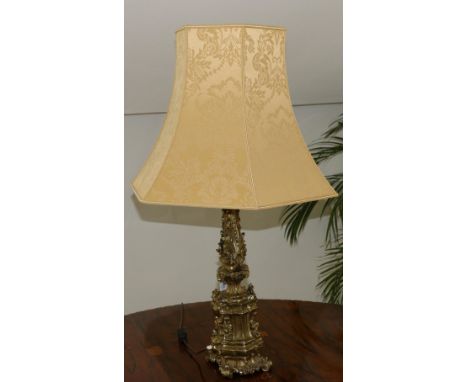 A gilt metal candlestick as a table lamp in Renaissance style cast with classical ornament and scrolling foliage on scroll fe