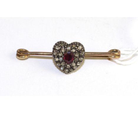 A ruby and diamond heart brooch, an oval cut ruby within a heart shaped cluster set throughout with rose cut diamonds in whit