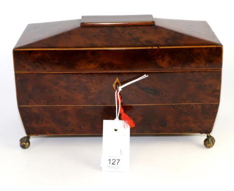 A Regency yew wood tea caddy, of sarcophagus form containing a glass bowl flanked by lidded compartments on claw and ball fee