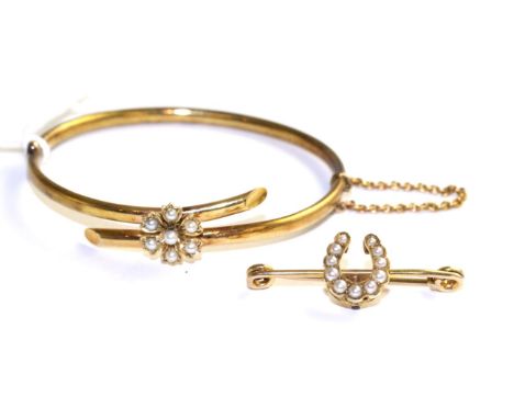 A seed pearl bangle, formed of two cross over bars with a central floral cluster set with seed pearls, to a plain hinged back