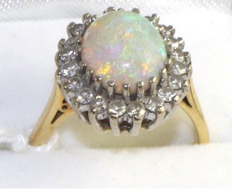 An opal and diamond cluster ring, an oval cabochon opal within a border of eight-cut diamonds in white claw settings, to yell