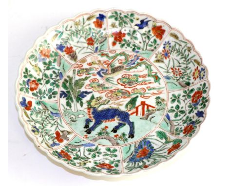 A Chinese porcelain dish, Kangxi, painted in famille vert enamels with mythical beasts and foliage in panels, 21.5cm diameter