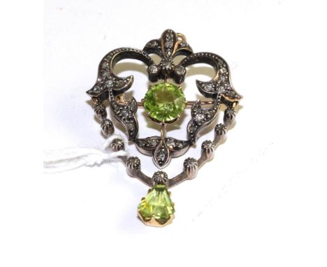 An Art Nouveau peridot and diamond pendant/brooch, the openwork scroll frame set throughout with od cut and rose cut diamonds