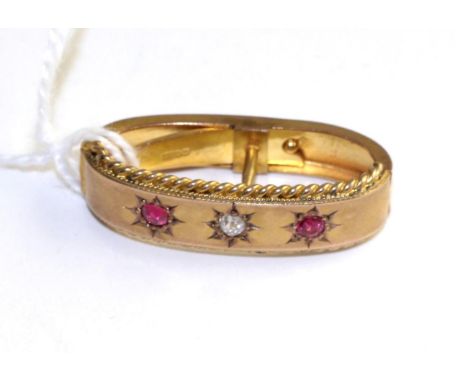 A 9 carat gold diamond and ruby scarf clip, an old cut diamond between two round cut rubies in star settings and within a rop
