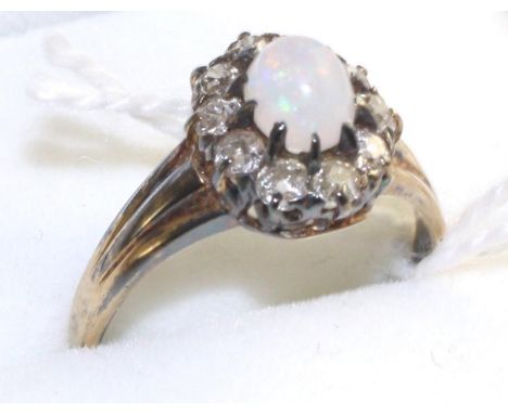 An opal and diamond cluster ring, an oval cabochon opal within a border of old cut diamonds in white claw settings, on a yell