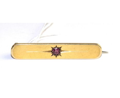 An 18 carat gold bar ruby bar brooch, a round cut ruby in a star setting to a plain bar, length 4.5cm The brooch is in good c