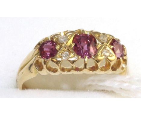 An 18 carat gold ruby and diamond ring, three graduated oval cut rubies spaced by rose cut diamond accents, in a yellow carve