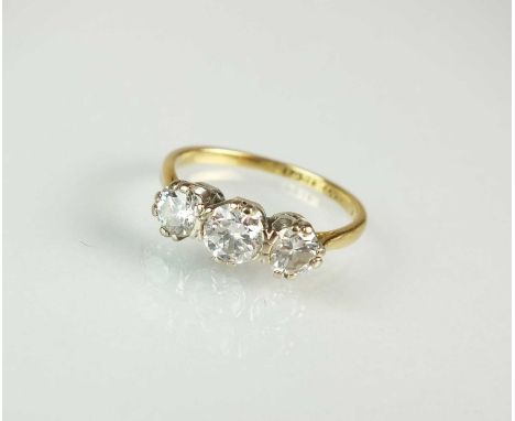 A graduated three stone diamond ring, the brilliant cut diamonds claw set in white metal to yellow metal shank, stamped '18ct