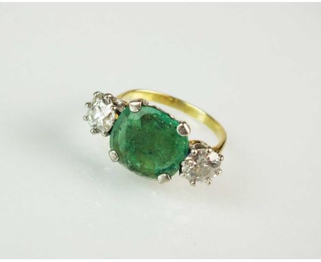 A three stone emerald and diamond ring, designed as a central oval mixed cut emerald with foil back mount, flanked to each si