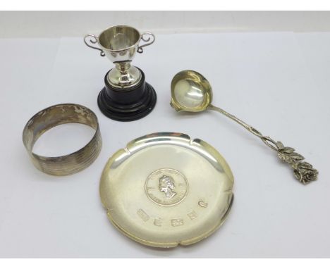 A 1977 silver dish, a silver napkin ring, an 835 silver spoon and a small silver trophy, 61g 