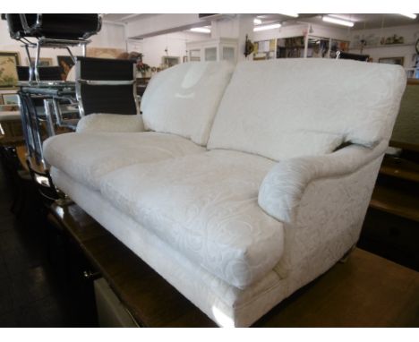 A WHITE UPHOLSTERED TWO SEATER SOFA