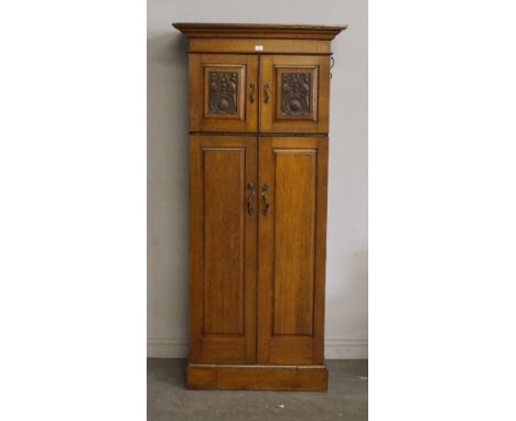 An Art Nouveau oak hall robe, having a moulded cornice and plain frieze above two short carved panel doors, with two long pan