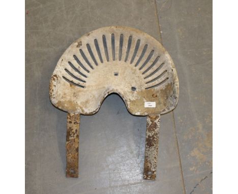 An old tractor seat, 43cm x 60cm, rusted and with concrete residue