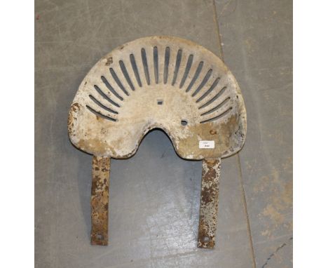 An old tractor seat, 43cm x 60cm, rusted and with concrete residue