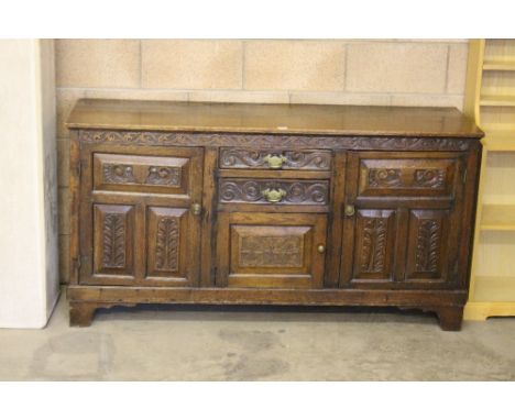 A Georgian oak dresser base, the rectangular top above two central drawers with panelled door below flanked by triple fielded