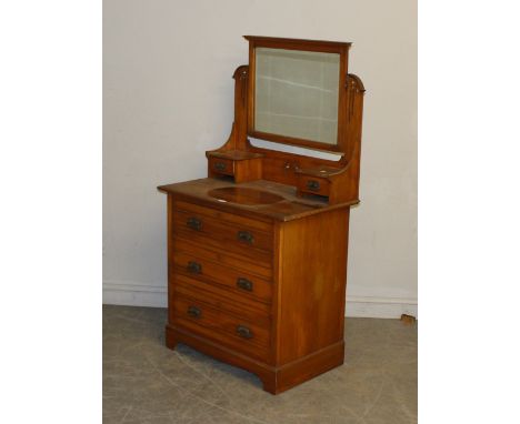 An Edwardian walnut dressing chest, the rectangular mirror plate between arched and pierced supports with shelves below, the 