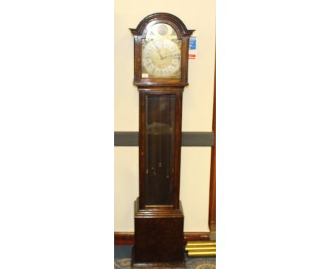 A 1930's three train oak long cased clock, having a moulded arched hood with glazed door enclosing the silvered chapter ring 