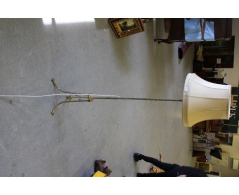 An Eastern cast-brass standard lamp, cast throughout with stylised foliate designs, raised on three down swept legs, the base
