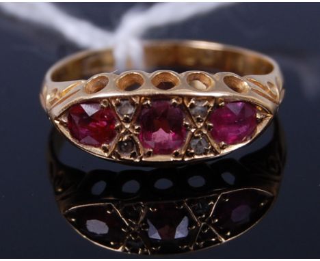 An 18ct gold, ruby and diamond dress ring, arranged as three old cut rubies, each divided by twin diamond points, 2.6g, size 
