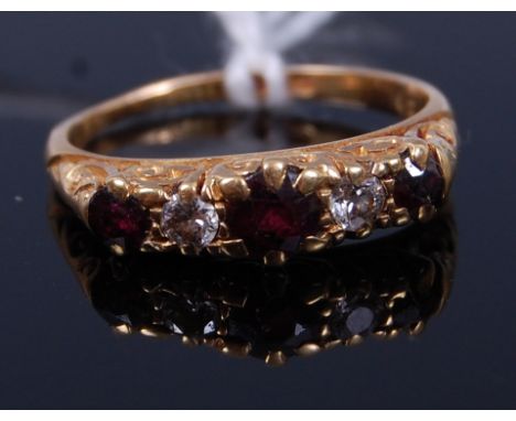 An 18ct gold, ruby and diamond set five stone ring, the three round cut rubies in a chased line setting, each dispersed with 