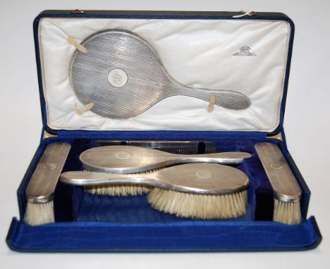 A George V silver backed six piece ladies dressing table set having engine turned decoration in fitted blue velvet lined leat