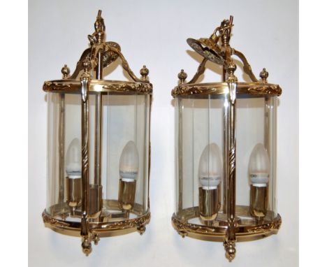 A pair of modern brass framed glass three-light ceiling light fittings