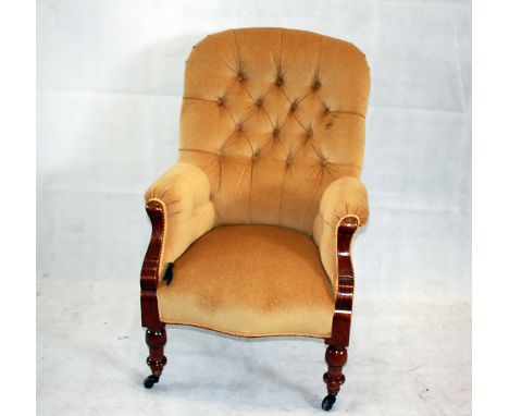 A mustard yellow upholstered button back armchair, on ceramic and brass casters 