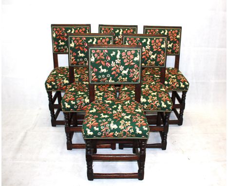 A set of six early 20th century oak Puritan style dining chairs, with tapestry upholstery of hounds, hares and deer within a 