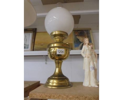 A brass oil lamp with opaque glass shade.