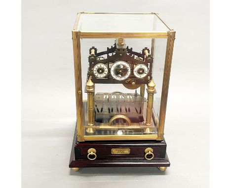 A brass and glass cased Congreave style clock mounted on a wooden base, 39.5 x 23 x 23cm.