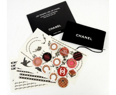 A collection of vintage Coco Chanel promotional badges for lipstick  (12) in a black  cotton dustbag, together with a set of 