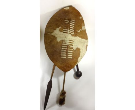 A Zulu Umbumbulu battle shield, 20th CenturyThe brown and white shield with knobkerrie, assegai spear and mgobo, height of sh