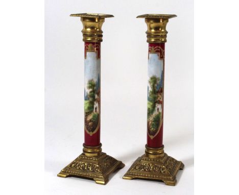 A pair of 19th Century ceramic and gilt spelter candlesticksOf cylindrical form, painted with rural scenes, height 24cmCONDIT
