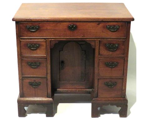 A George III mahogany kneehole deskOf typical form, with one long and six short drawers and a central door, raised on bracket