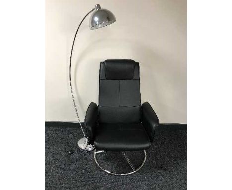 A black swivel armchair together with a chrome metal floor lamp