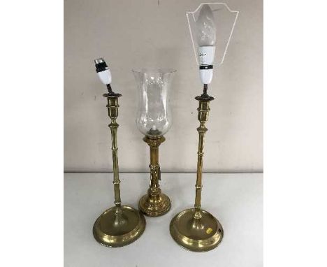 A 20th century brass rise and fall hurricane candlestick and a pair of converted brass lamps 