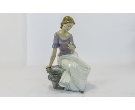 Nao By Lladro, young lady sat down holding a flower. Height 11.5 inches.