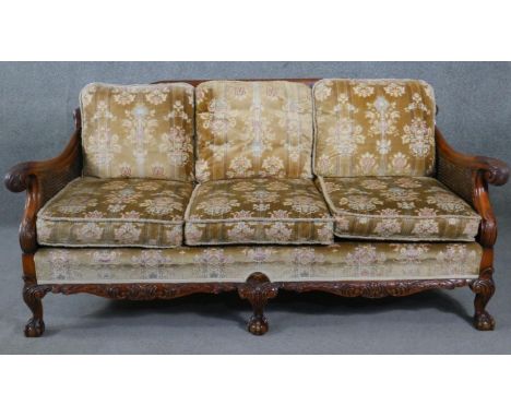 A mid century carved walnut three seater bergere sofa with double caned sides in cut floral upholstery and with scroll arms r