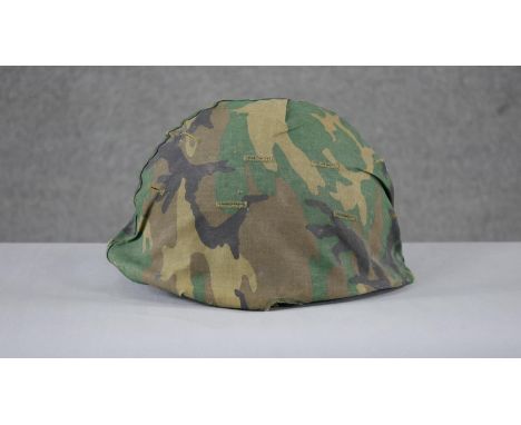 A WW2 US Schlueter helmet with camouflage canvas hood liner. H15 W.24 D.28cm 
