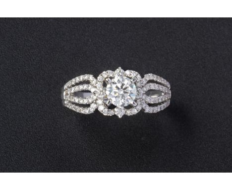 A DIAMOND RING
The design featuring a round brilliant cut diamond with four rows of diamonds set to each shoulder
The central