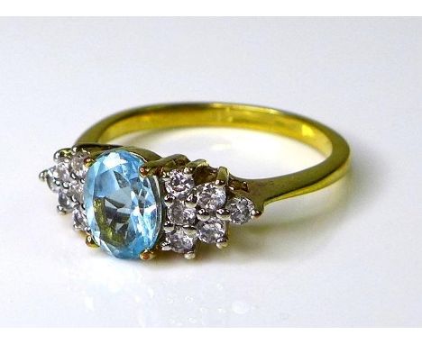 An aquamarine dress ring, the oval central stone flanked by a cluster of six white stones to either side, possible white sapp